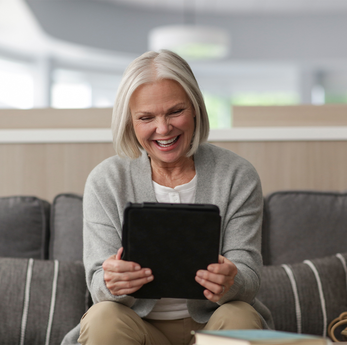 woman sitting on couch smiling looking at tablet