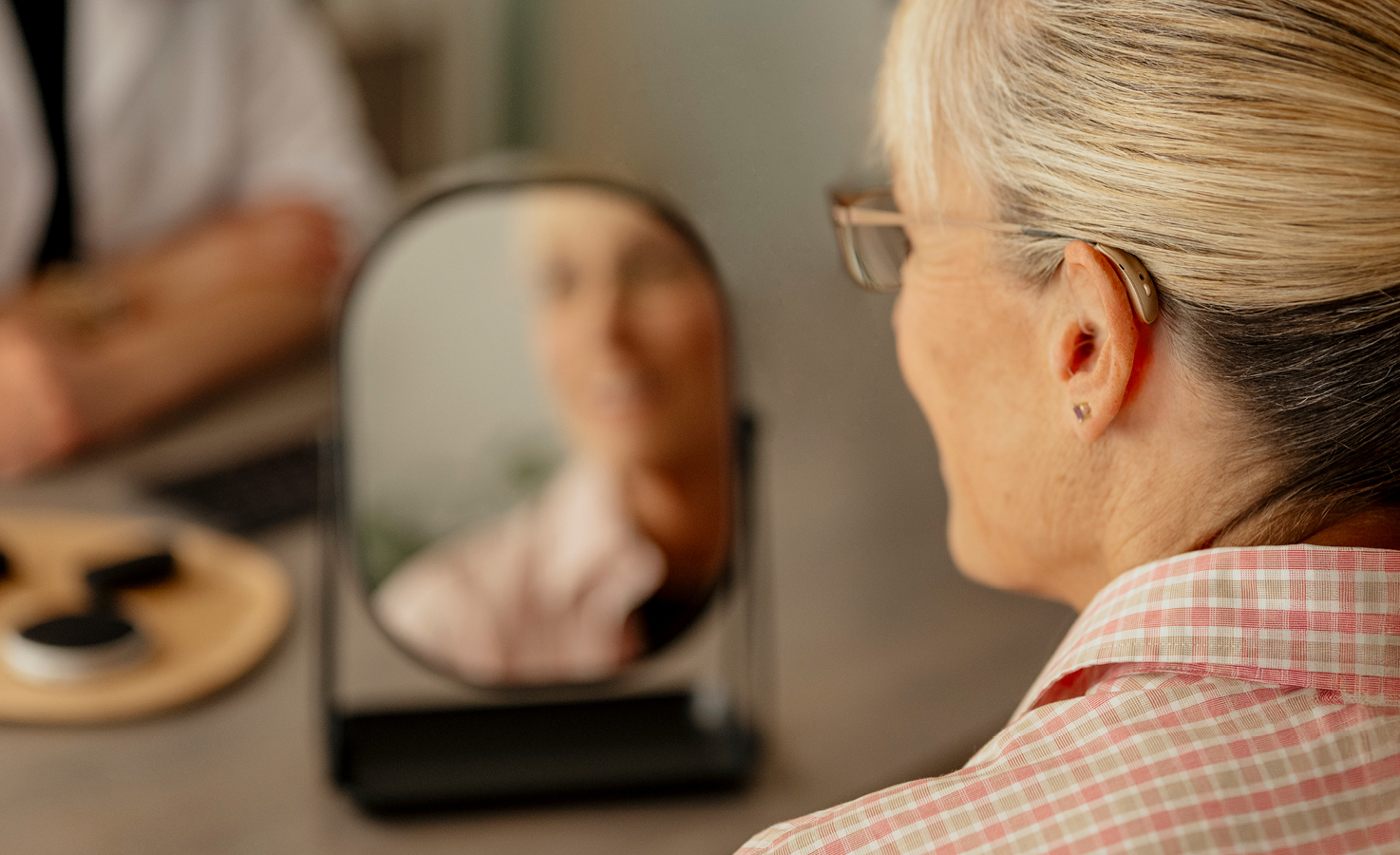 Woman trying on hearing aids smiling in the mirror.